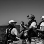 Fulvia tend un nourrisson de quatre mois à son collègue Père, marin sauveteur. L’enfant, en arrêt respiratoire, sera réanimé par le sauveteur quelques secondes plus tard sur le pont du bateau. 27 juin 2022.